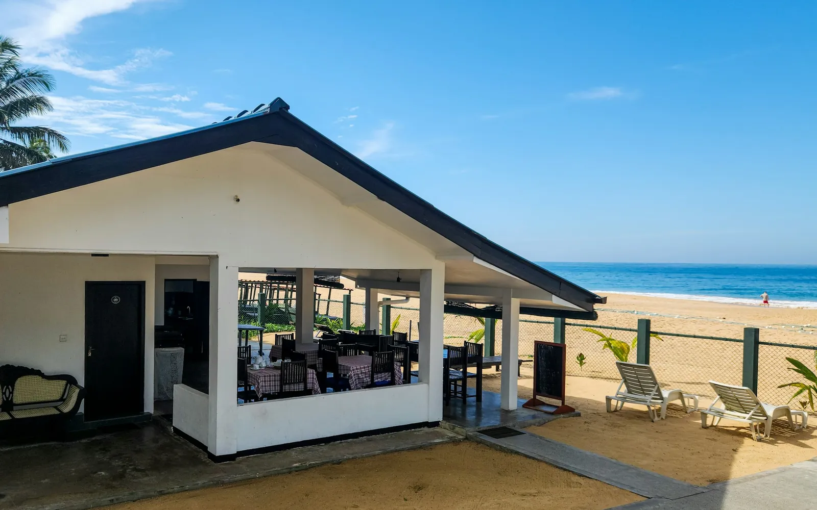Terasă de restaurant pe plajă, cu mese și vedere la mare