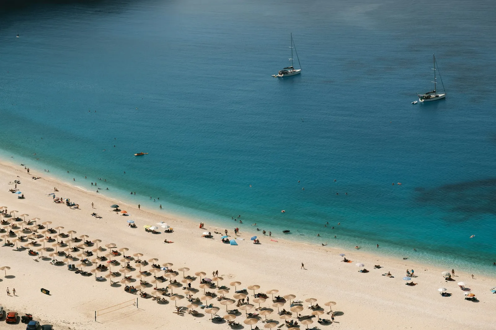 Plajă însorită cu umbrele și mare turcoaz, văzută de sus